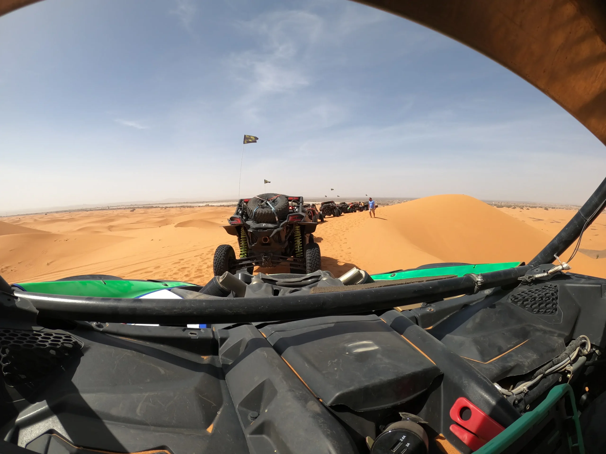 Widok z kierownicy pojazdu 4x4 na wysokie pomarańczowe wydmy pustyni Sahara.